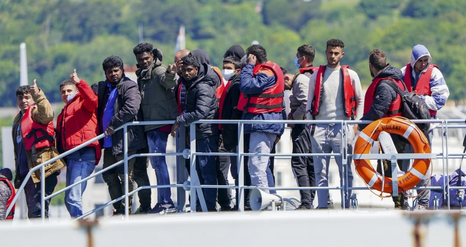 Migrants gesture as they arrive in port on Border Force boat Valiant after attempting the crossing of the English Channel from France on June 14, 2022