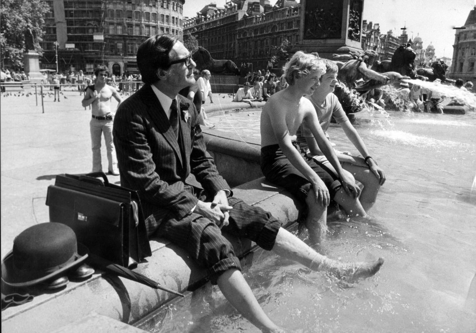 1976 Summer Heatwave, scenes around London as temperatures soar. Keeping cool in Trafalgar Square, a city gent takes off his shoes and dips his feet into the fountain with a bowler hat and umbrella next to him. 24/06/1976