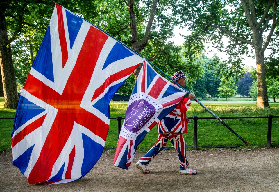 A man with a flag walks along The Mall in central London ahead of the troops parade