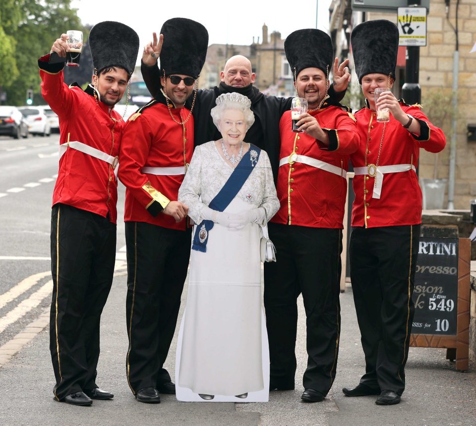 Mates in Beefeater costumes pose with a cardboard cut-out of Her Majesty