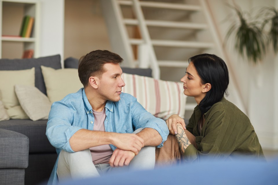 Warm toned portrait of modern young couple talking to each other sincerely while sitting on floor in cozy home interior, copy space; Shutterstock ID 1686595822; purchase_order: -; job: -; client: -; other: –