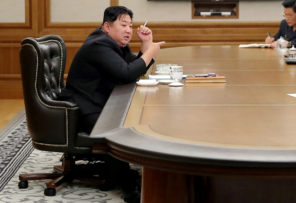 Kim Jong Un puffs on a cigarette at a meeting after firing long-range guns into the sea