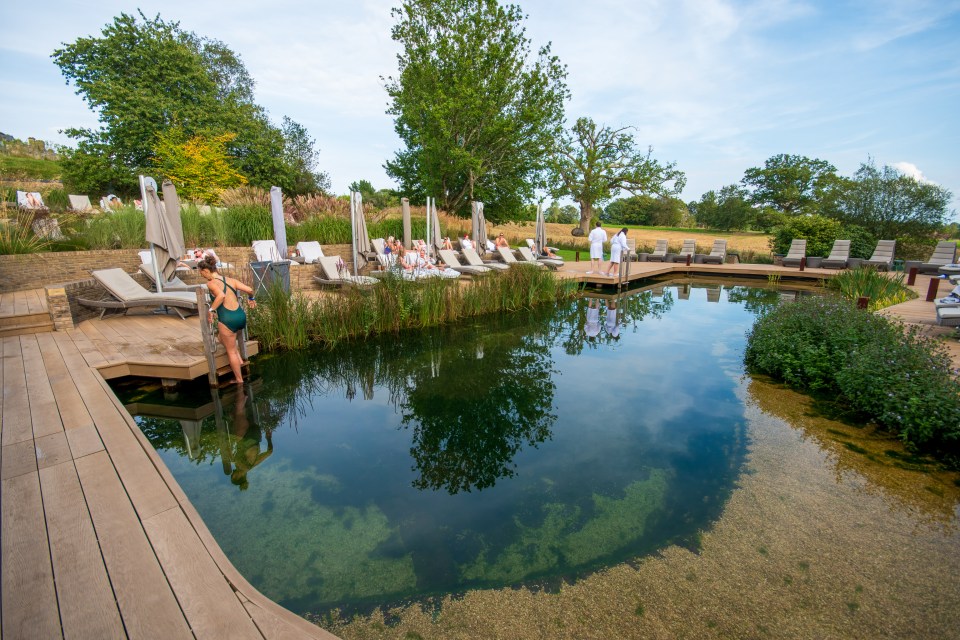 a woman in a bathing suit walks into a large pond