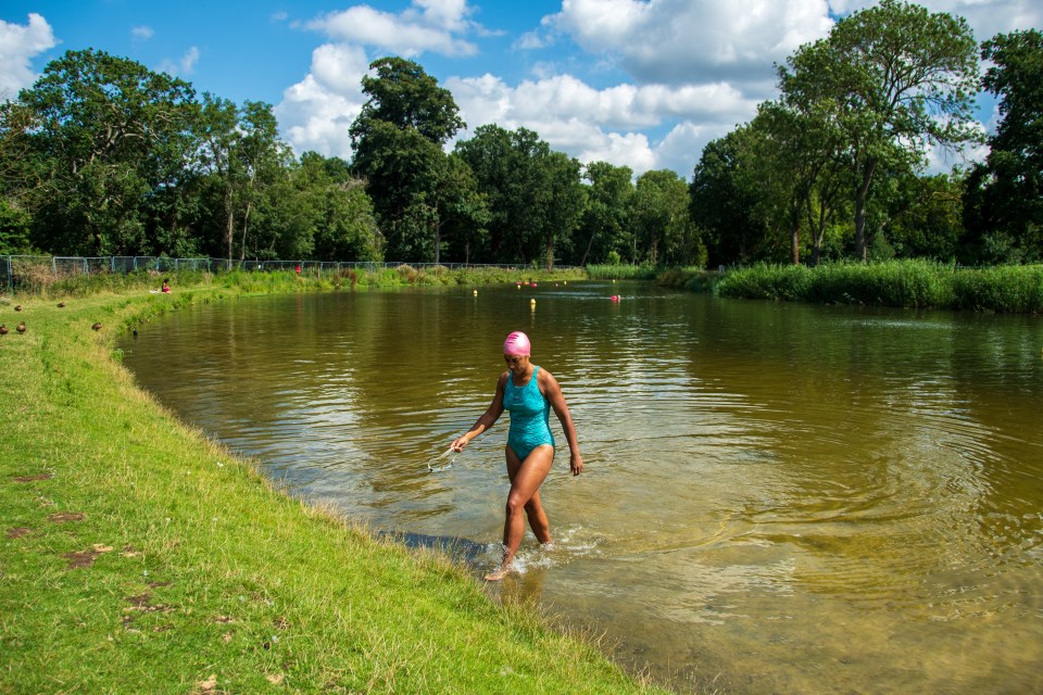 a woman in a blue swimsuit is walking into a lake