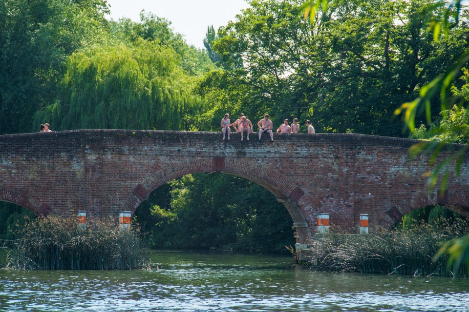 a group of people sit on a bridge over a river