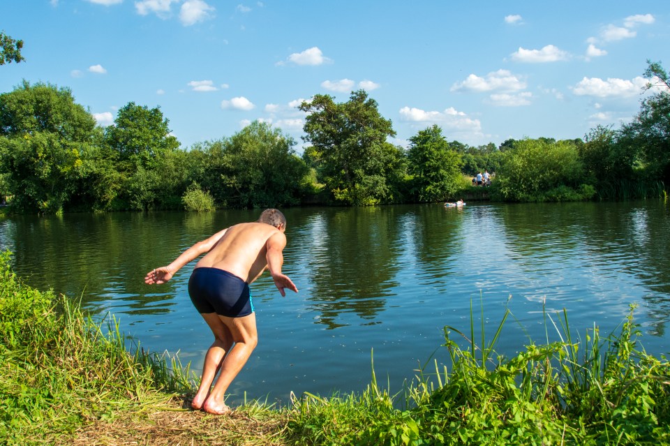 a man without a shirt is diving into a lake