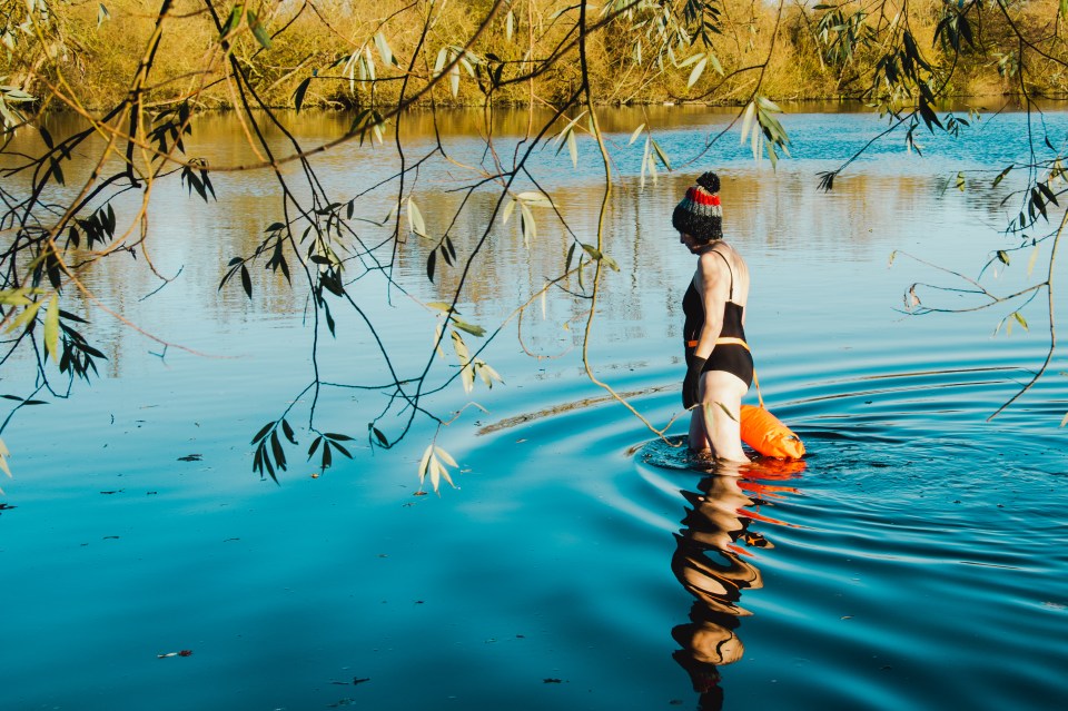 a woman in a black bathing suit is standing in a lake