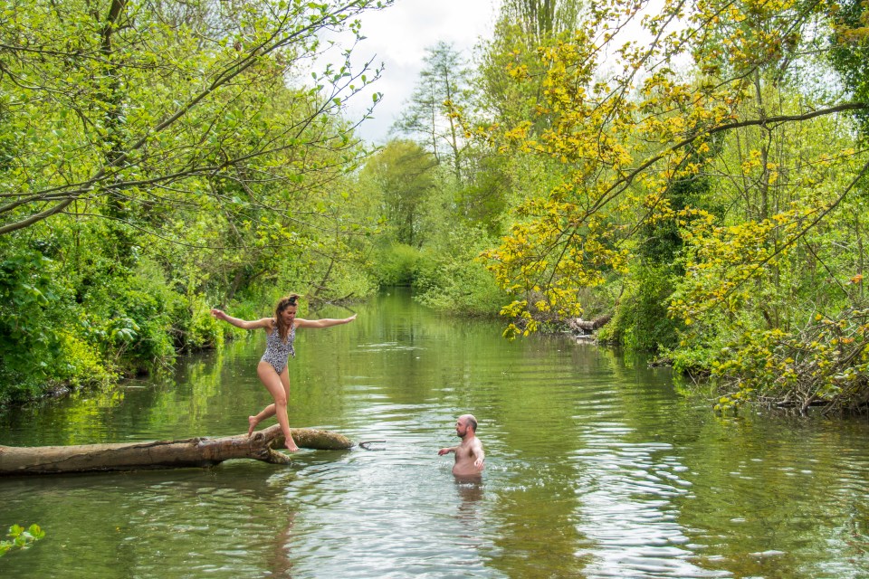 a woman in a bathing suit stands on a log in a river