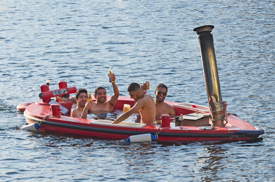 A group of lads enjoyed the cooling breeze and a beer in a floating hot tub in Canary Wharf