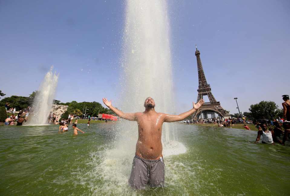 A man cools off in the shadow of the Eiffel Tower in Paris, France as the country faces record temperatures