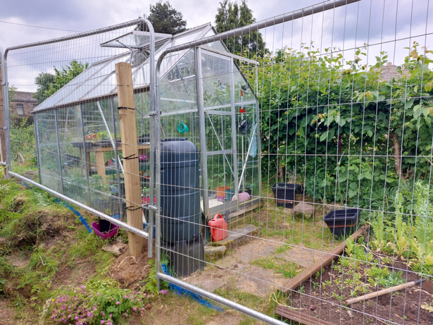 A woman claims builders have put an 8ft fence in the middle of her garden