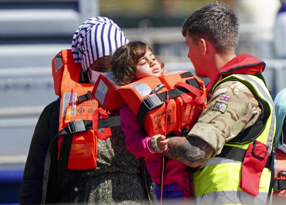 A soldier carries a young child ashore from Border Force boat Valiant after attempting the crossing of the English Channel from France on June 14