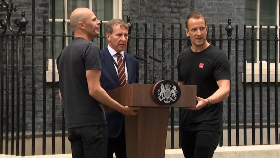 A man, right, dressed in all black helped set up the podium before Boris Johnson's resignation speech