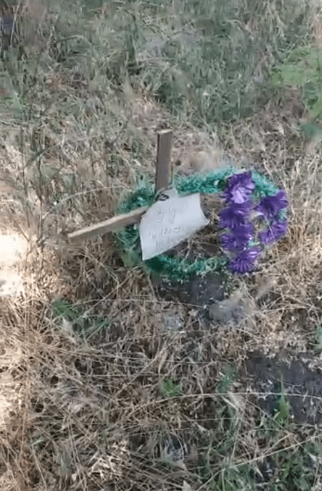 A cross hastily decorated stands on the site of a mass grave in Mariupol’s Livoberezhnyi district