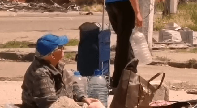 An old man waits for a water delivery in a city without any water supply system