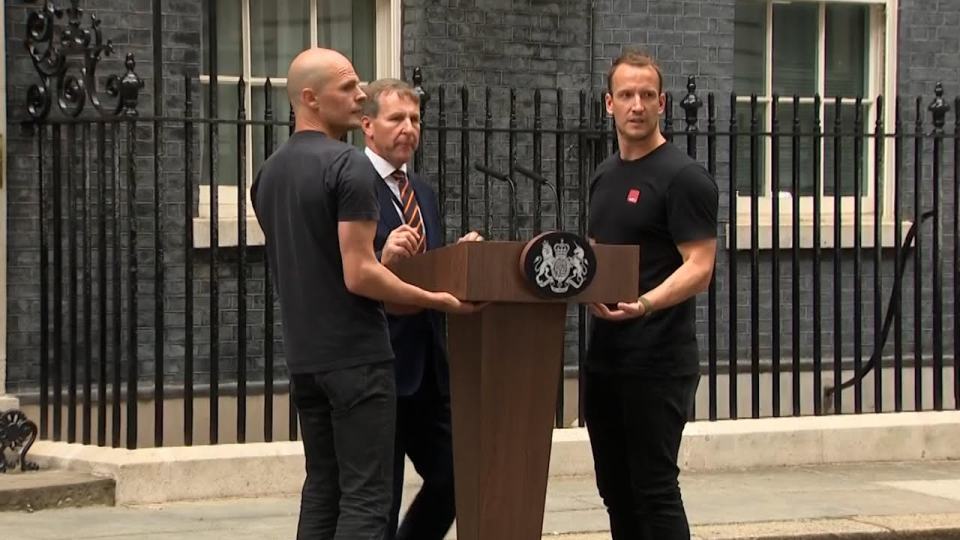 'Hot podium guy', right, had help carrying the podium into place