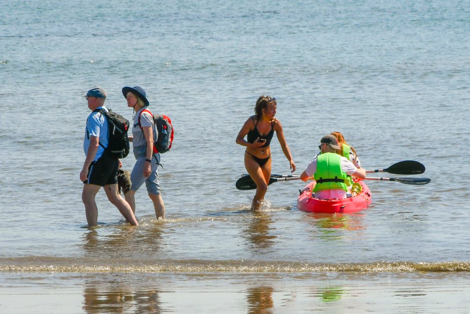 Beachgoers paddling at the seaside resort of Lyme Regis in Dorset