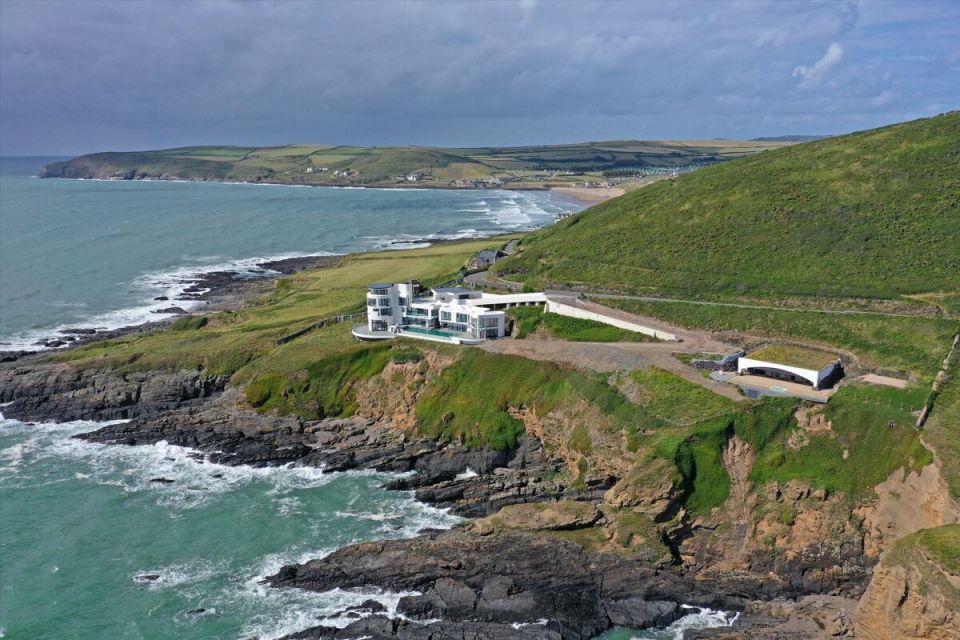 a large white house sits on a cliff overlooking the ocean