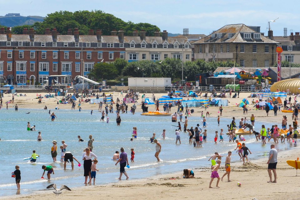 Beach goers cool off in the sea at Weymouth in Dorset