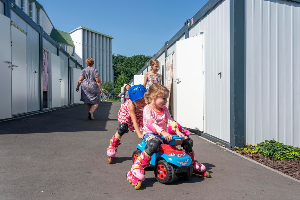 Two youngsters play on rollerskates in a makeshift village made of shipping containers for displaced Ukrainians