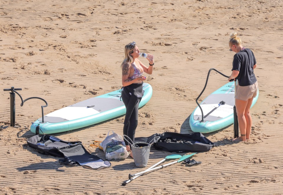 Two ladies pump up their paddle boards in Cullercoats Bay in North Tyneside on Wednesday