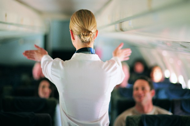 a stewardess on an airplane with her arms outstretched