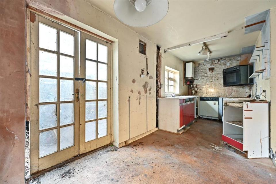 The kitchen has been gutted, with only a microwave, boiler, stove and red cupboards remaining