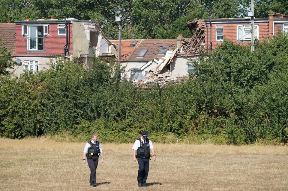 Cops patrol the scene with the collapsed home in Thornton Heath clearly visible in the background