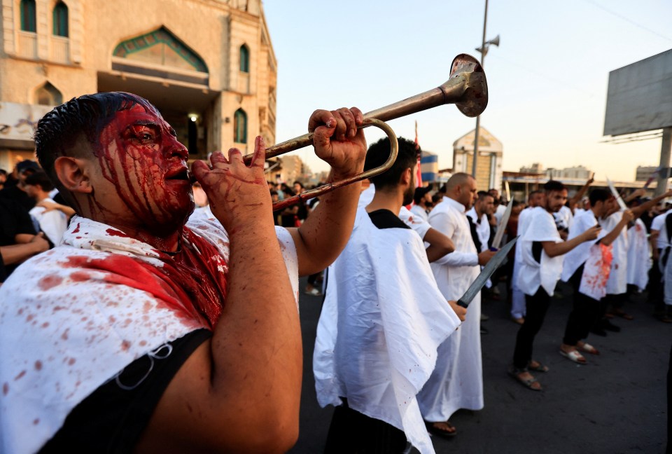 A man blows a horn while his face is covered in blood in Baghdad