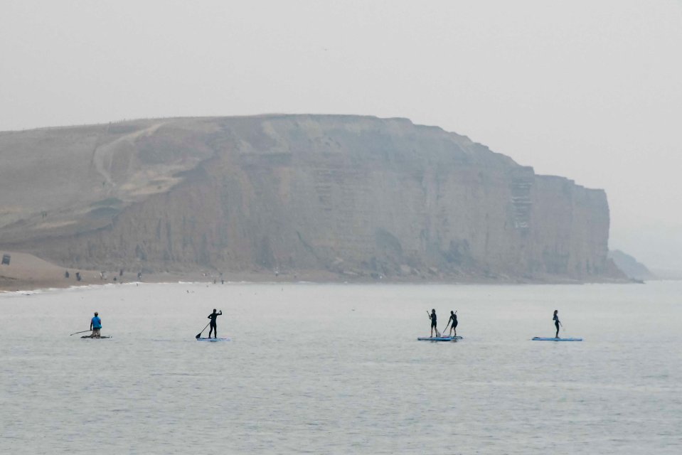 Paddleboarders in Dorset grinned and bared against the wet weather