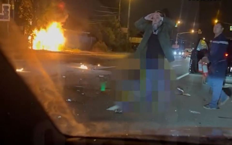 Alexander Dugin with his daughter's burning car behind him