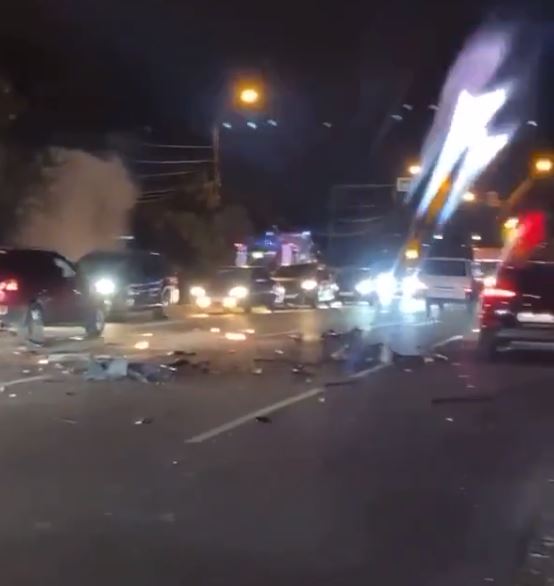 Cars drove over the busy road that was littered with debris from the blast