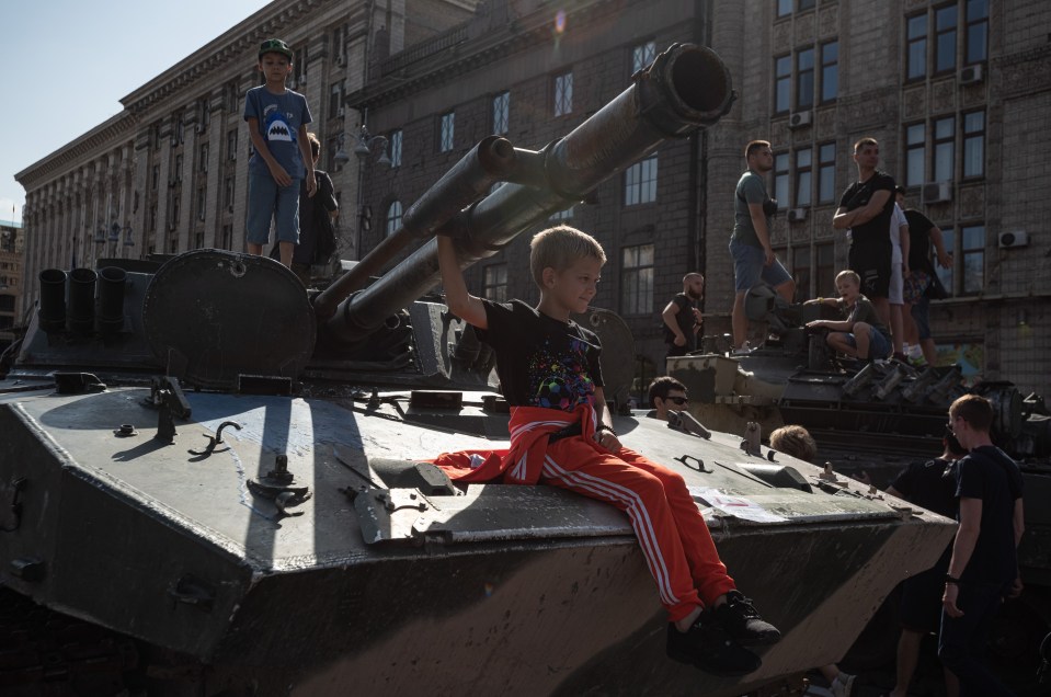 A boy poses for a picture on top of a tank