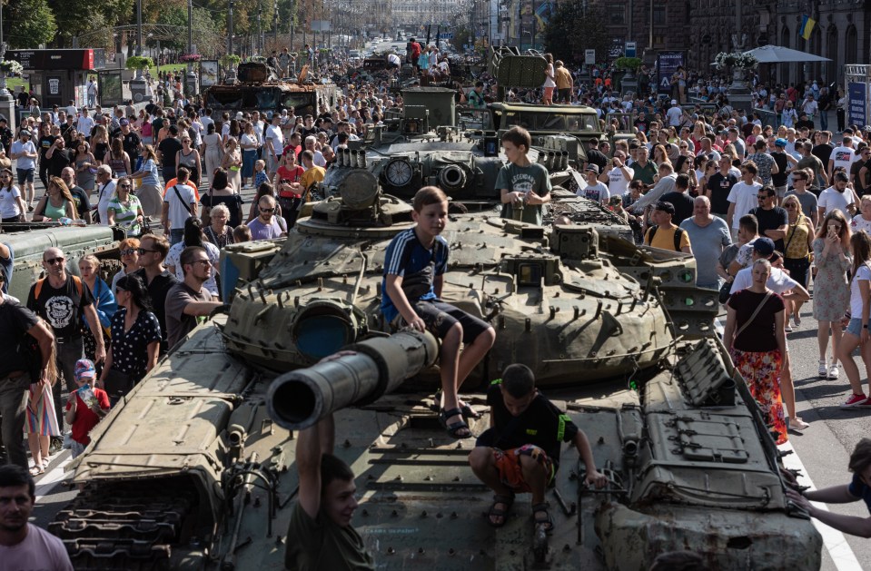 People walk by burnt Russian military vehicles displayed in Kyiv