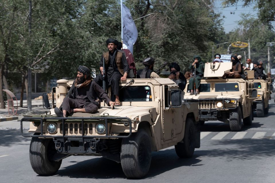 Armed Taliban fighters parading atop Humvee vehicles