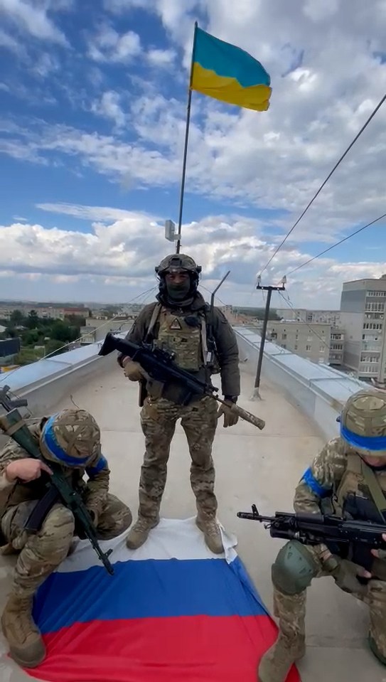 A Ukrainian soldier standing on Russian flag as his country's one is raised