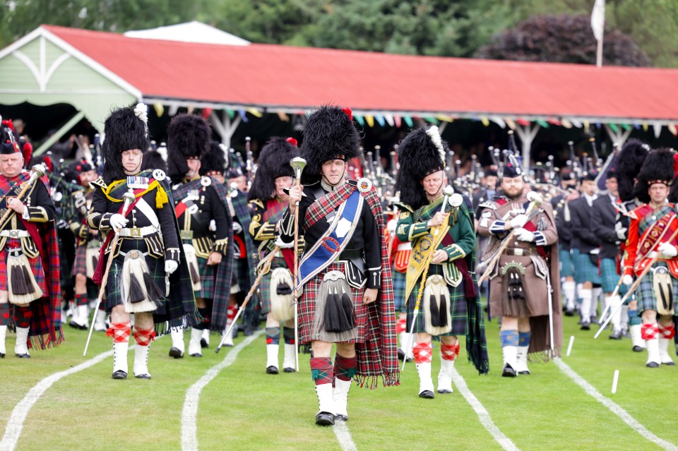 Drum Major Roland Stuart of the Police Pipe Band leads the procession