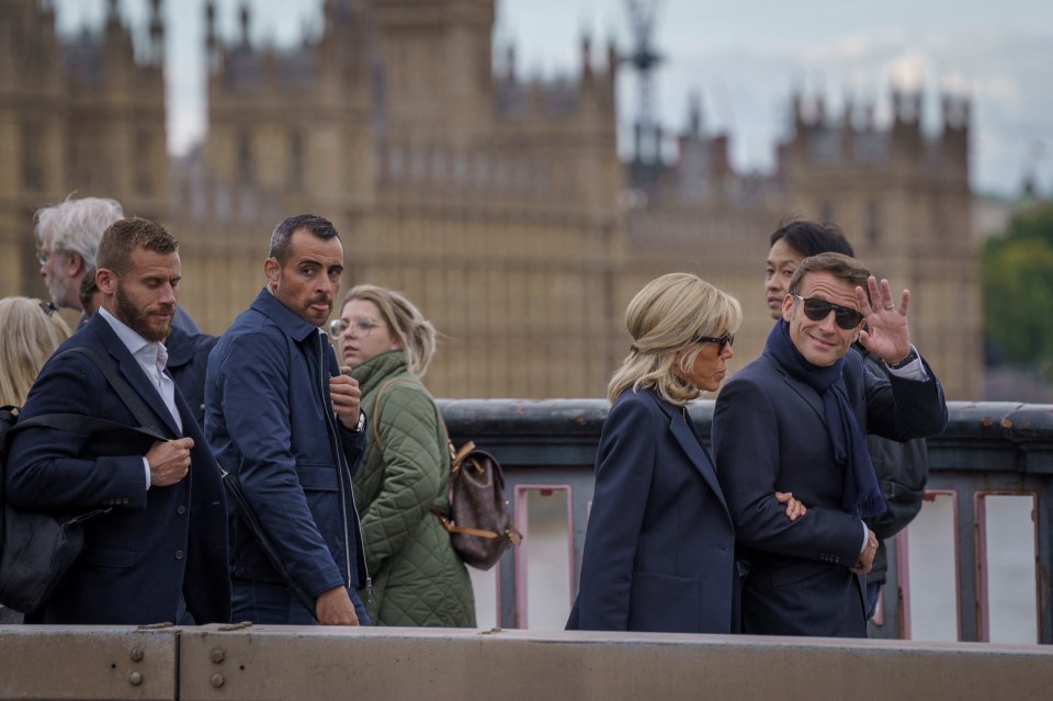 Emmanuel Macron and his wife Brigitte wave to the public as they walk near Westminster