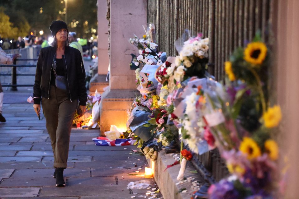 A mourner looks at the flowers laid in memory of Her Majesty outside Buckingham Palace