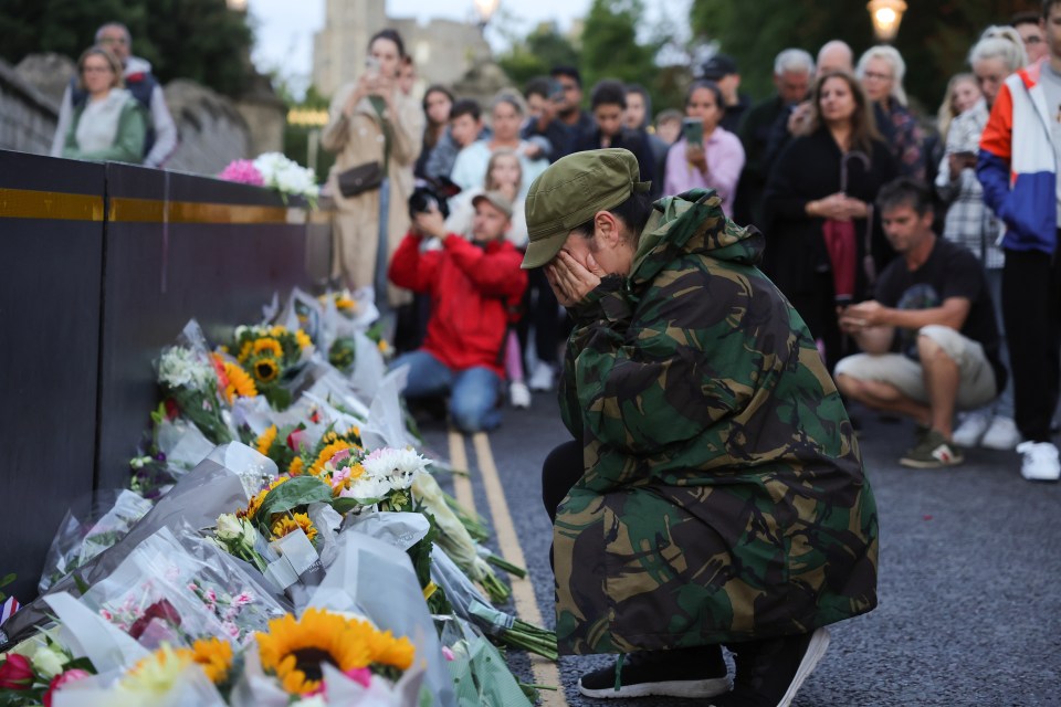 A mourner overcome with grief the gates of Buckingham Palace after laying flowers