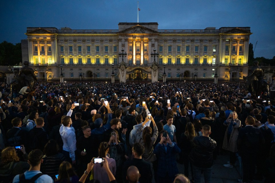 The Union flag flies half mast as people gather at Buckingham Palace