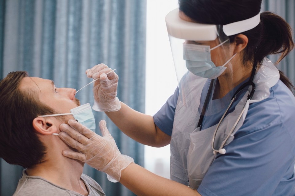 A nurse takes a swab to test for Covid