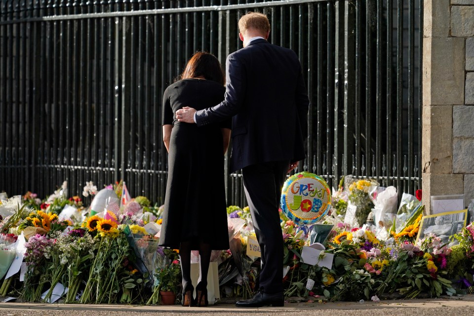 Harry also put his arm around his wife to view floral tributes