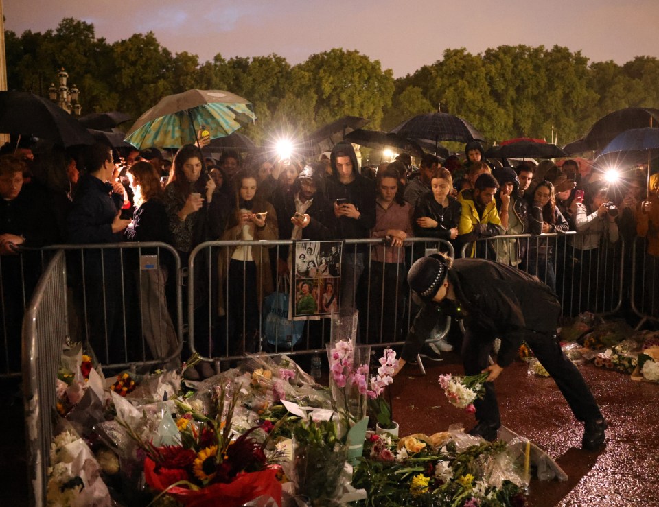 A police officer laying flowers outside Buckingham Palace