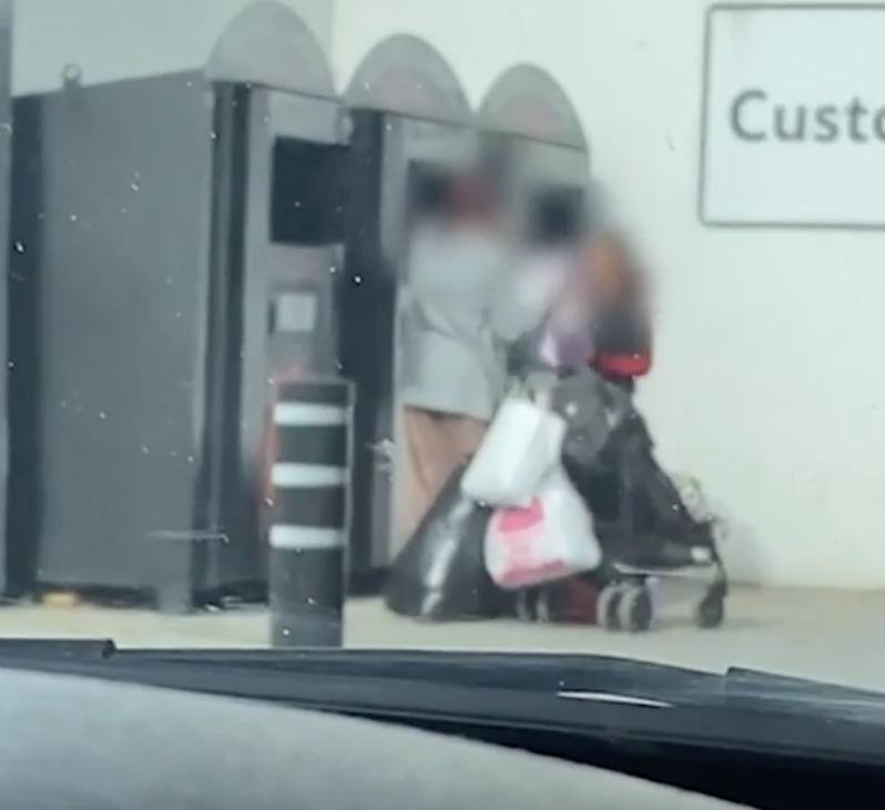 The woman pulls out a large plastic bag from inside the charity bin