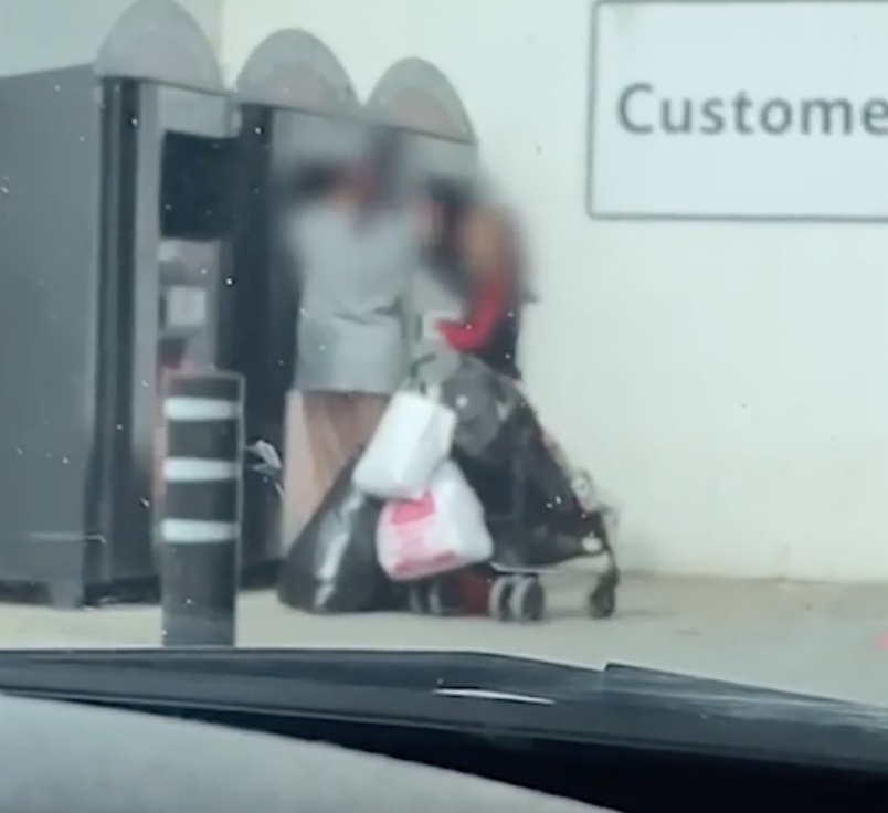 The woman is seen rummaging around in the bin while her friend looks on at the start of the footage