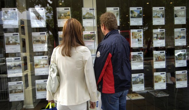 a man and a woman are looking at a display of houses for sale