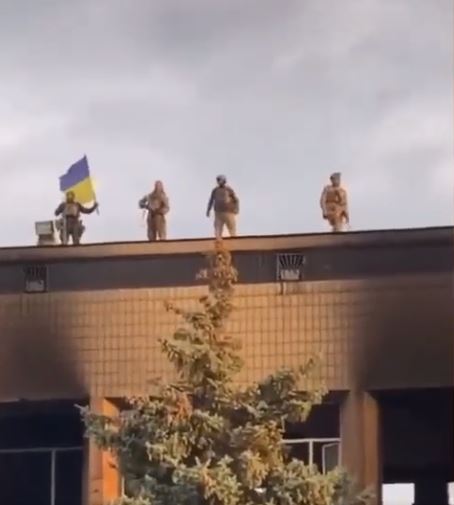 Ukrainian soldiers hold up a flag in Izyum after it was liberated