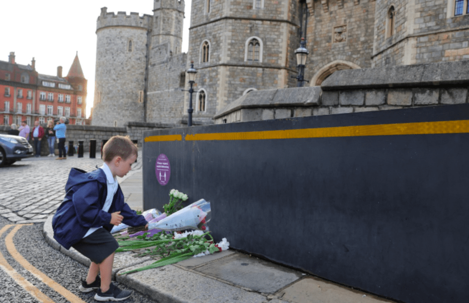 A young boy lays flowers in Windsor after it was announced that the Queen had passed