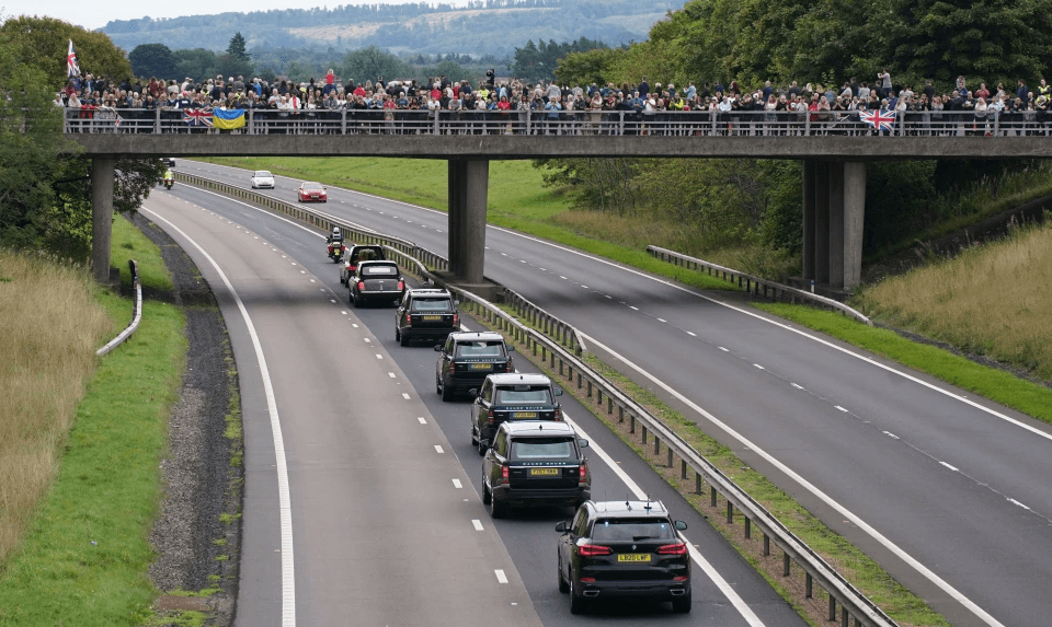 Well-wishers gather on the M80 motorway bridge as the procession passes